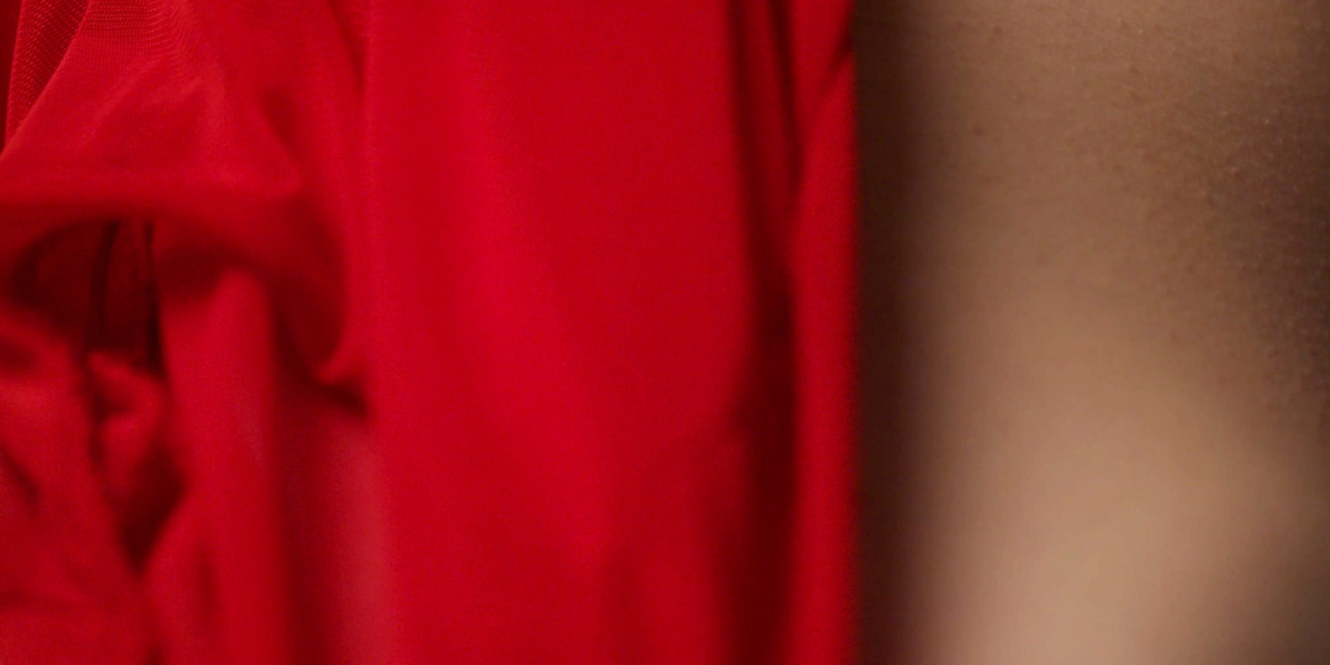 Zdjęcie macro 100mm, część czerwonej sukienki nocnej na kobiecej skórze z ciarkami. buduar
